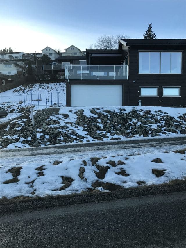 Nytt hus på ferdig tomt, med steinfylling ned mot veien.